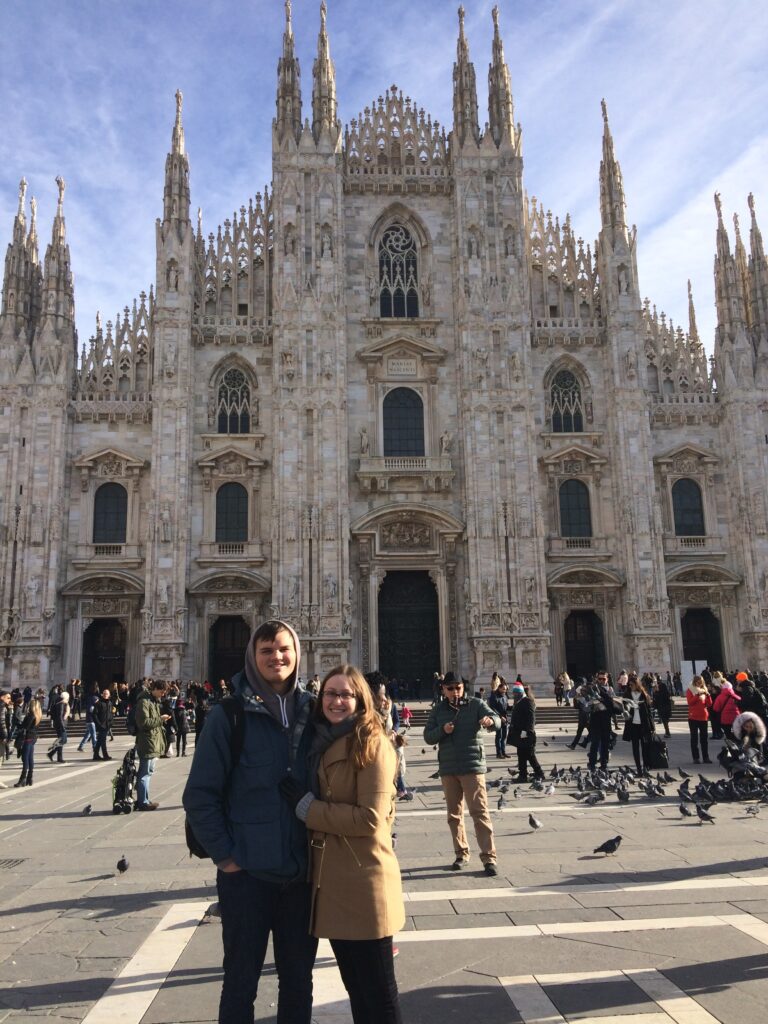 "Couple standing in front of the iconic Milan Cathedral (Duomo di Milano) in Milan, Italy
